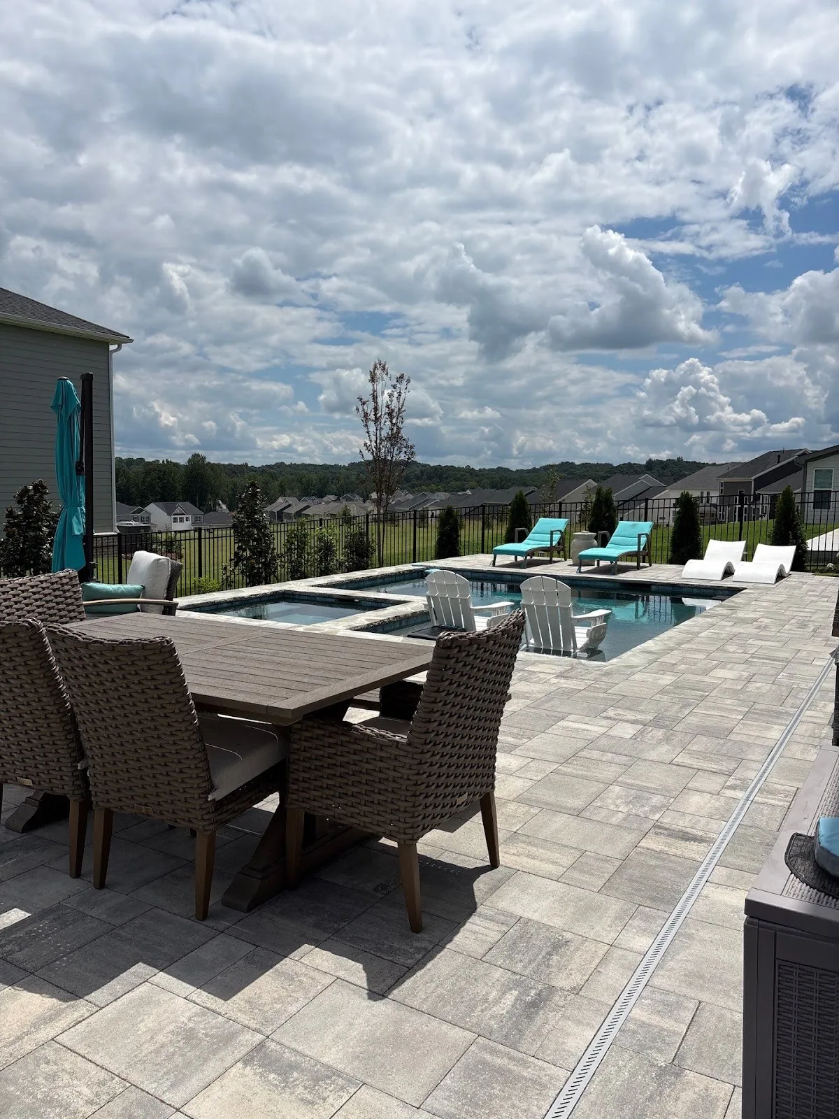 A stone paver pool deck surrounding a swimming pool during a hardscape installation in Hoschton, GA.